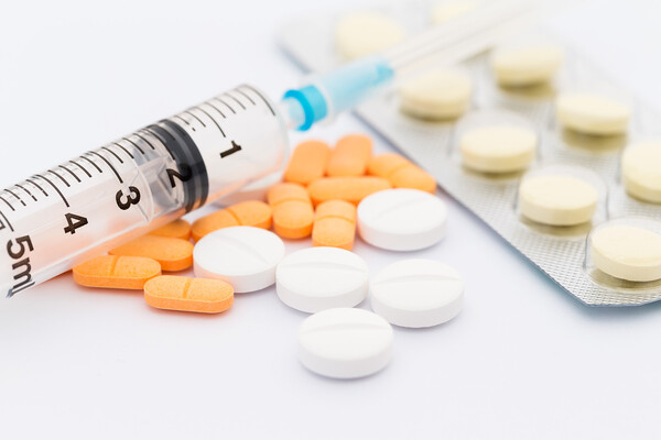 고혈압 환자가 감기약을 조심해야 하는 이유 관련 이미지 - 다양한 색상의 알약과 주사기가 함께 놓여 있는 의료 관련 이미지입니다. 질병 치료 및 건강 관리에 사용되는 의약품과 도구를 보여줍니다.