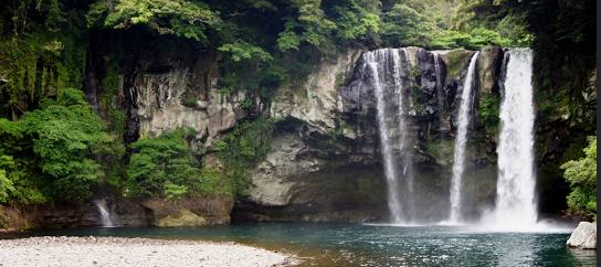 특징 관련 이미지 - 울창한 숲과 기암괴석 사이로 여러 줄기의 물줄기가 시원하게 쏟아져 내리는 아름다운 폭포 풍경입니다. 맑고 푸른 물이 고인 연못과 자갈밭이 어우러져 평화로운 자연의 모습을 보여줍니다.
